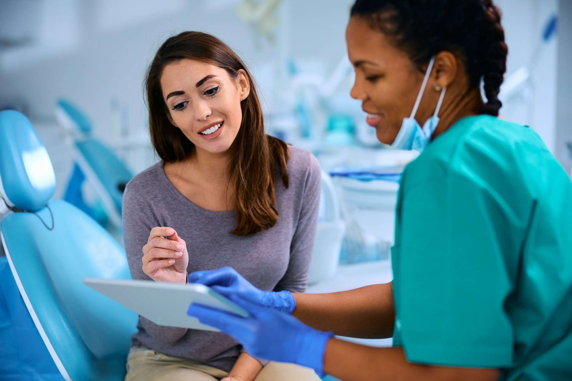 Smiling woman and her dentist using digital tablet during appointment at dental clinic.