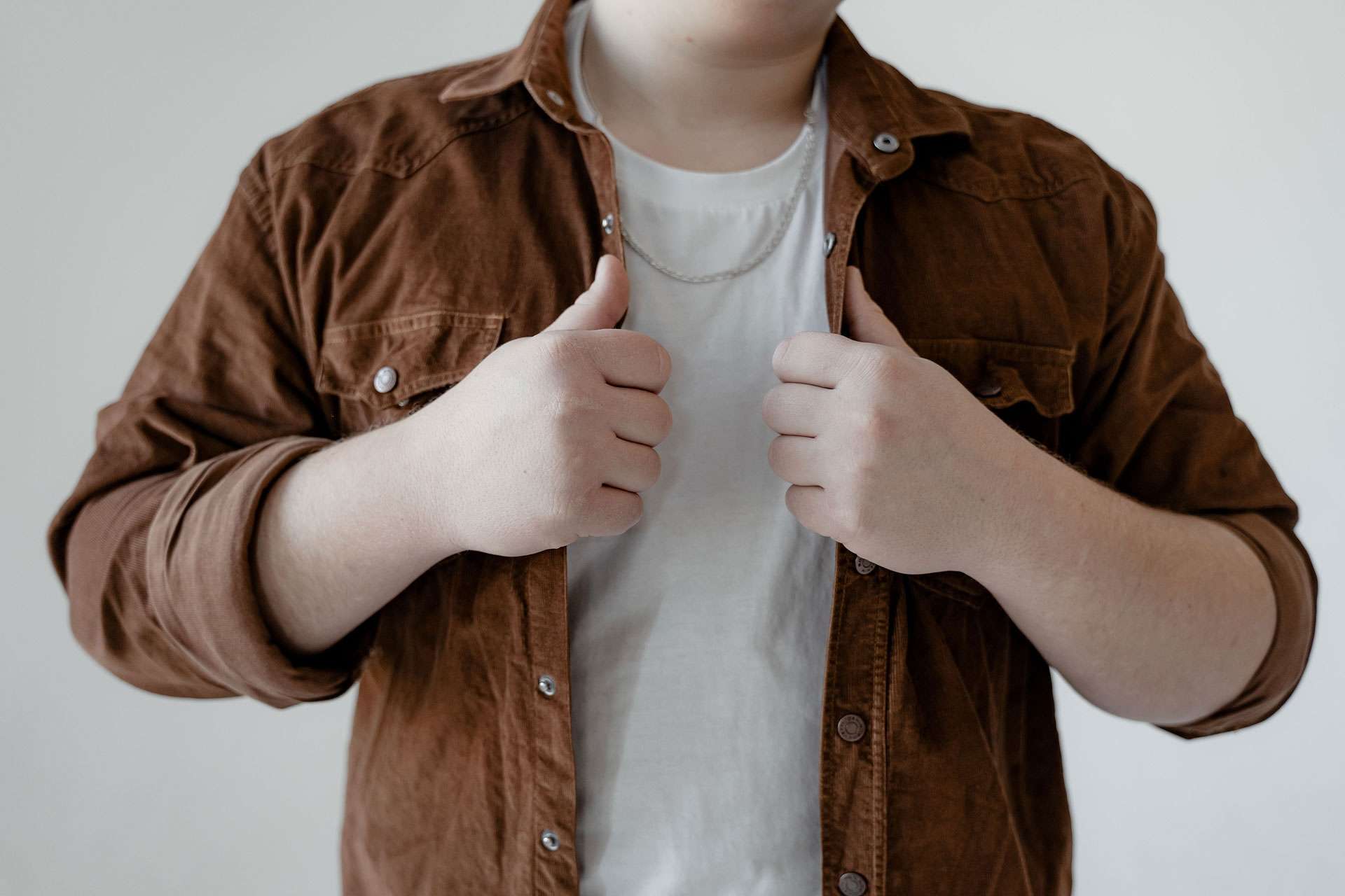 Slightly plus size person holding their shirt.