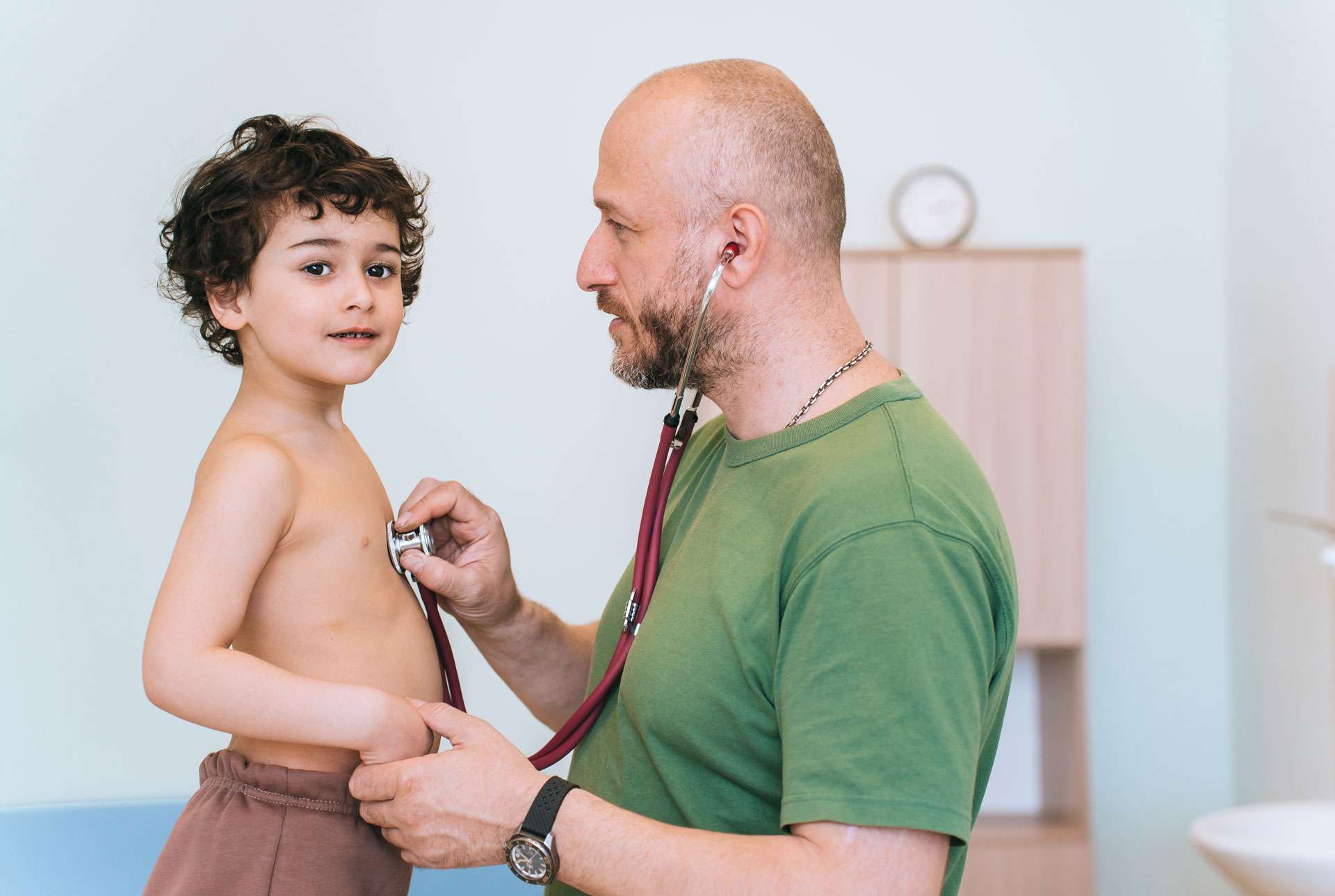 A healthcare professional listens to a young boy.