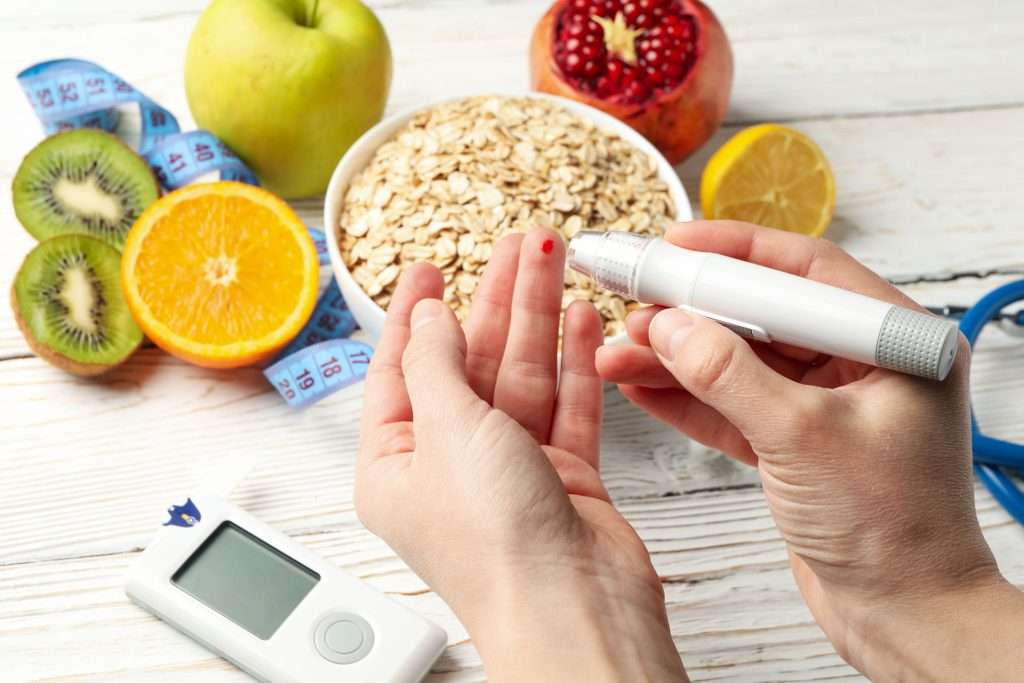 Woman checking her glucose level with healthy foods on background.