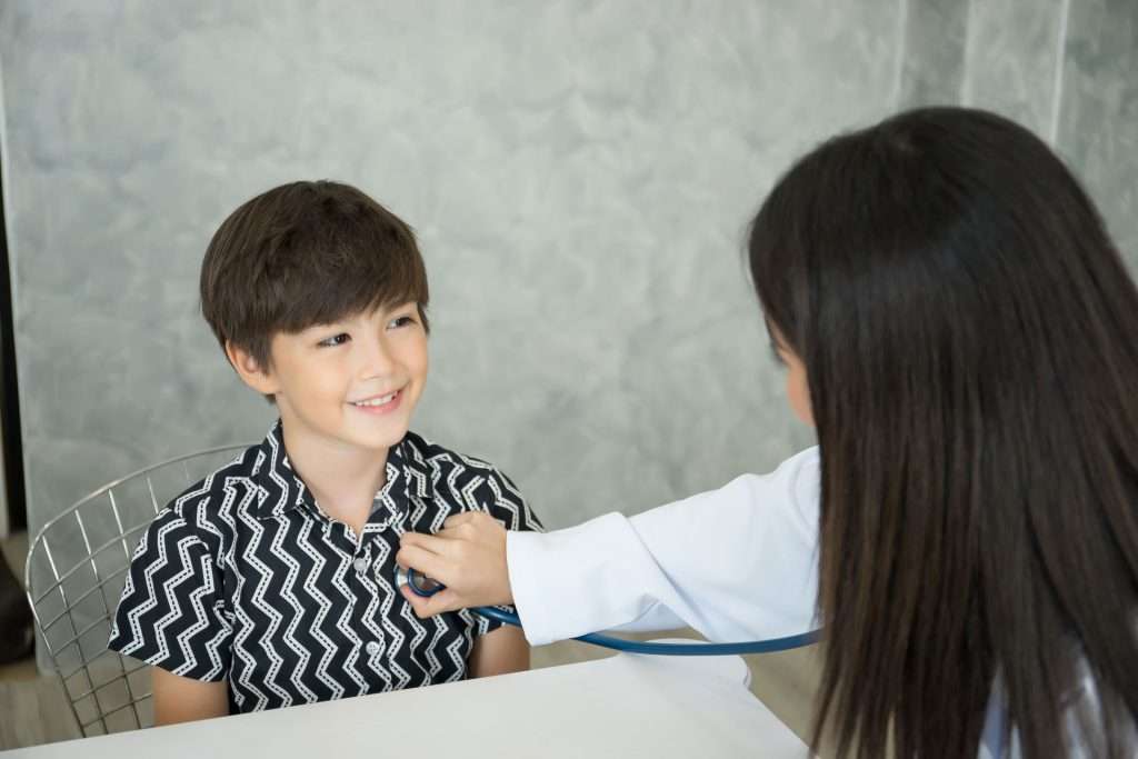 A female doctor with a stethoscope examining a boy.