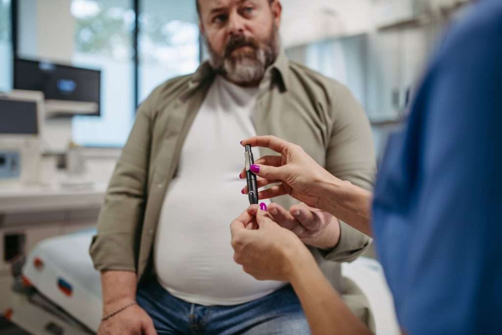 Nurse getting a man's blood for glucose level checking.
