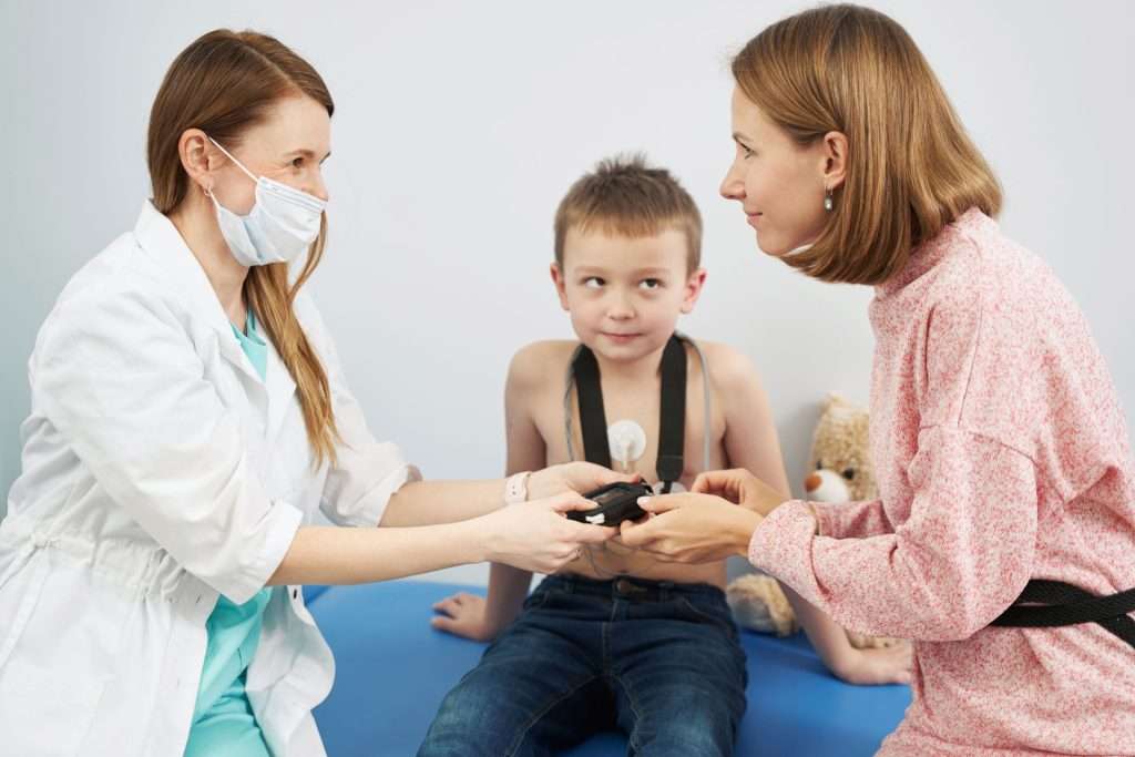 pediatrician checking a boy's heart with ecg.