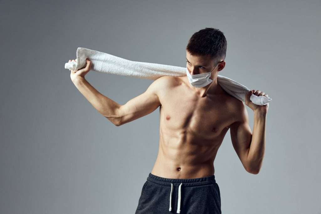 Fit man without shirt holding a towel.