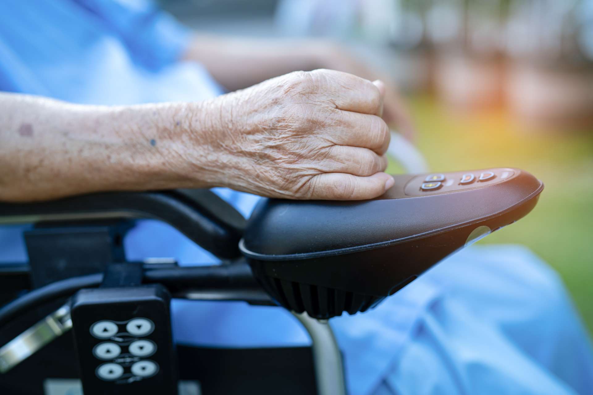 Senior patient sitting and controlling wheelchair.